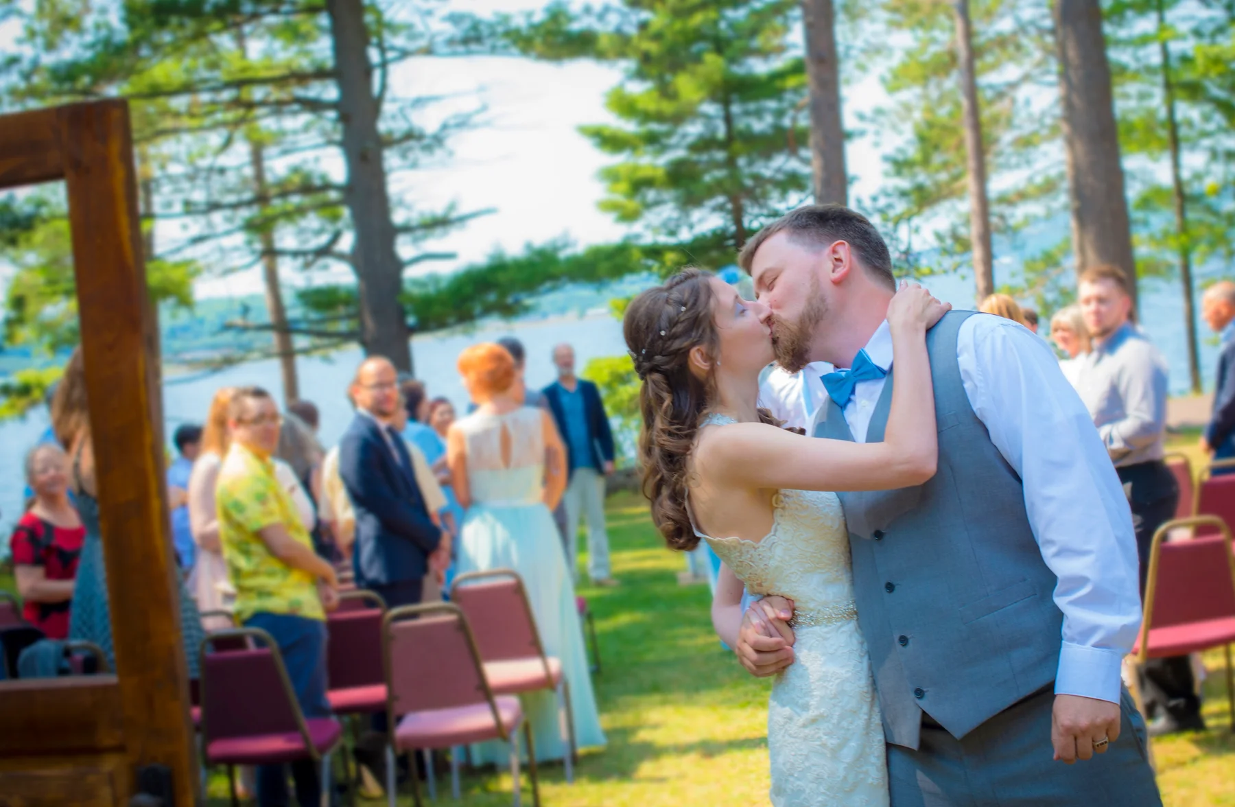 A couple kissing during an outdoor ceremony near a lake.