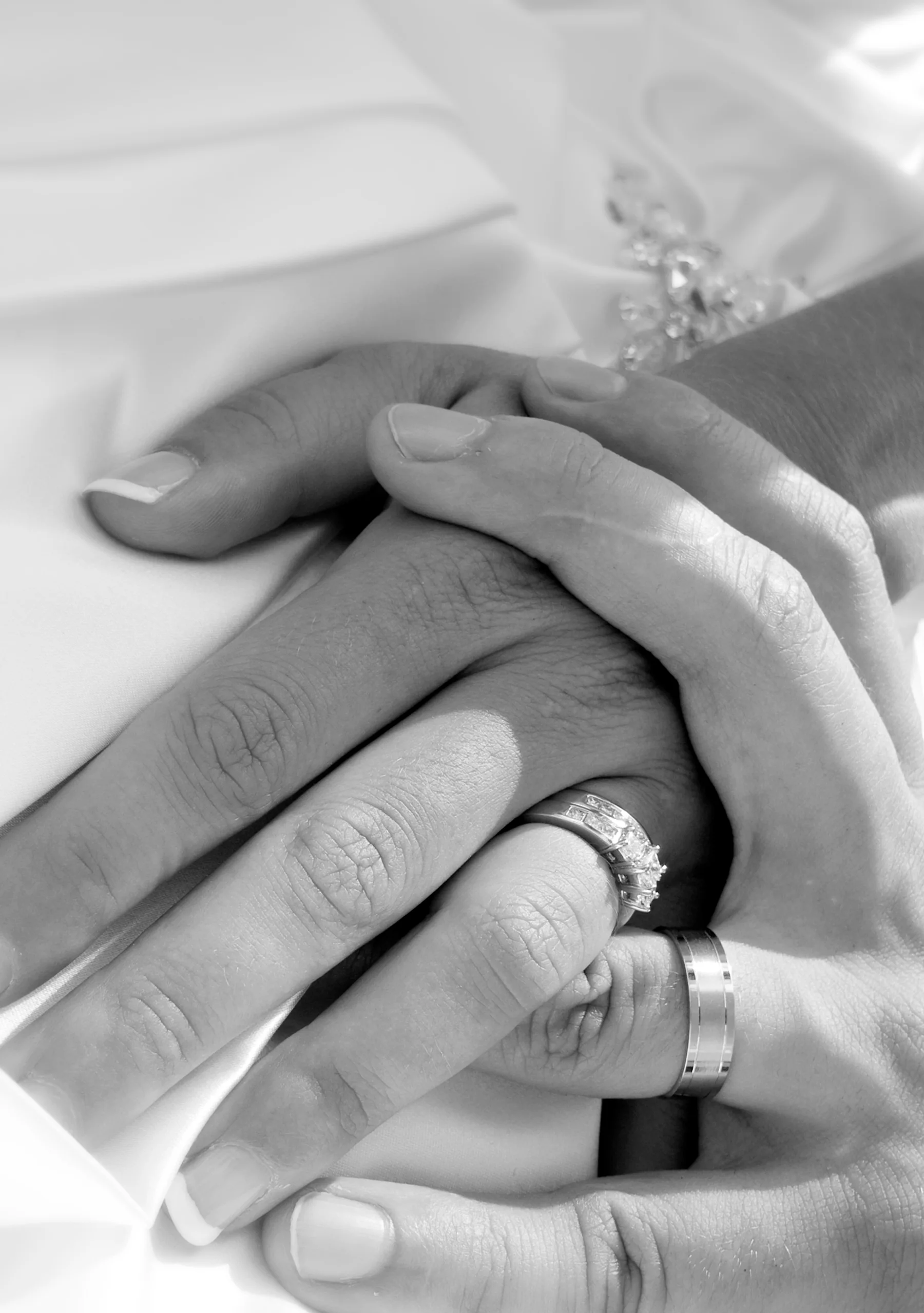 A close view of wedding rings and hands in black and white.