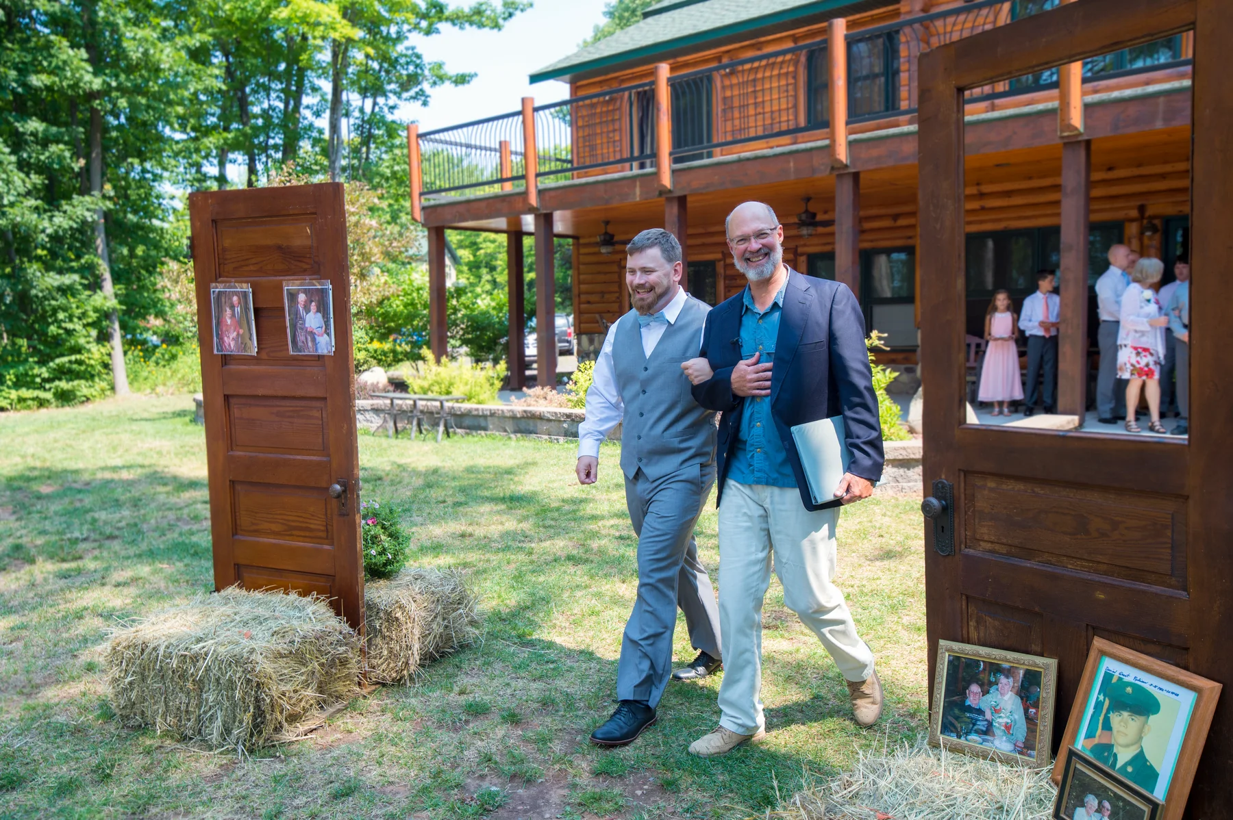 A groom walking through outdoor wooden doors with a wedding setting behind him.